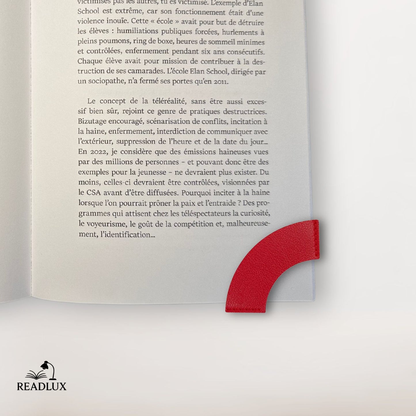 Un marque-page en cuir rouge en forme de cœur, placé dans un livre ouvert sur une page écrite