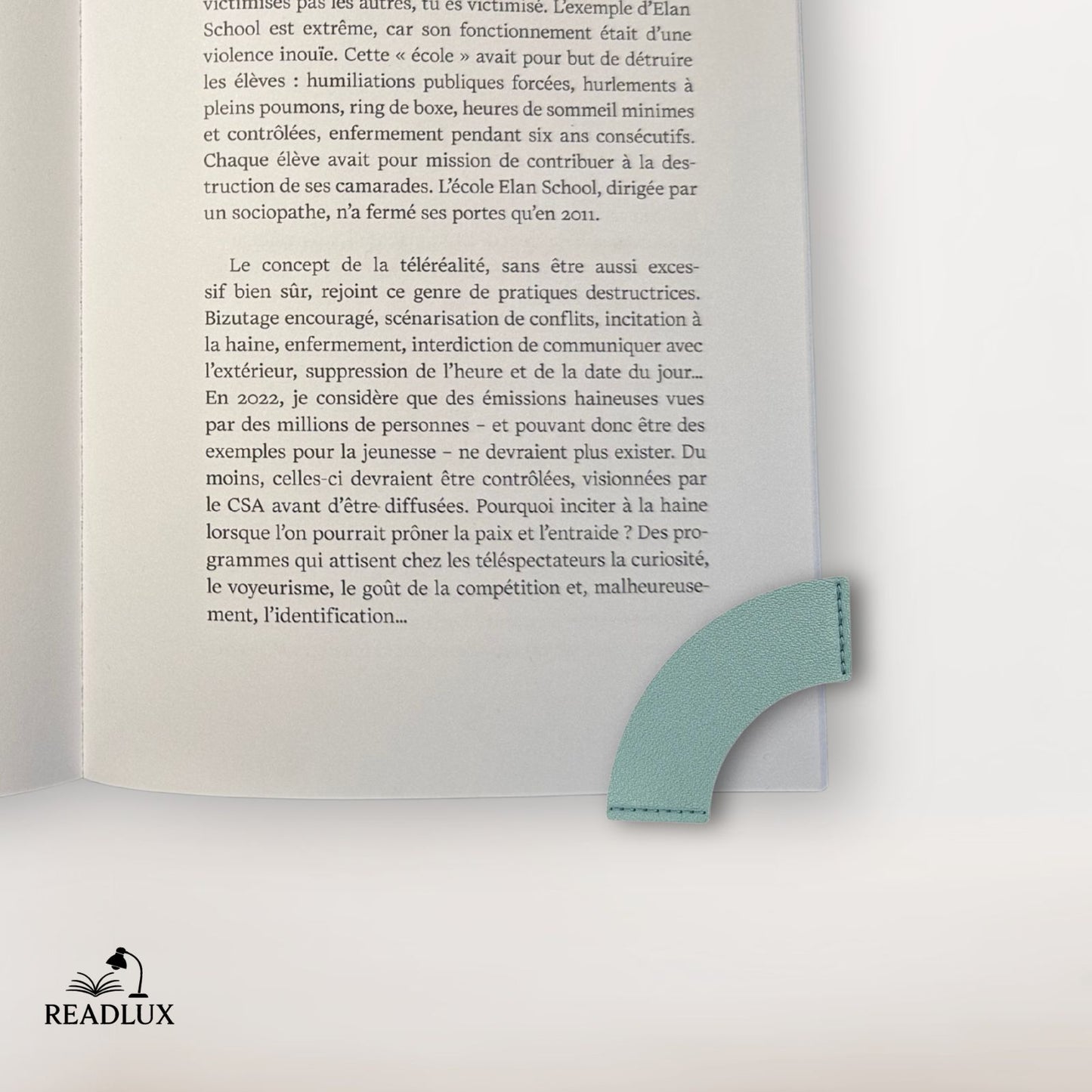 Un marque-page en cuir vert clair, en forme de cœur, posé sur une page d'un livre ouvert