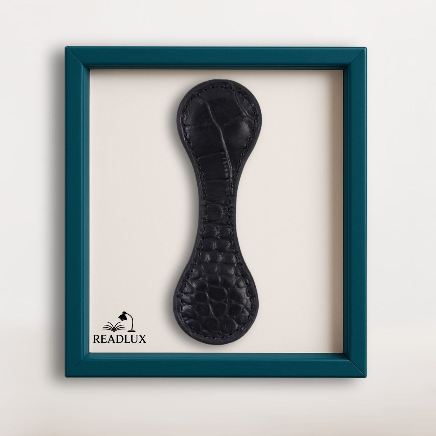Marque-page en cuir noir, avec une texture lisse et un design élégant, présenté dans un cadre turquoise