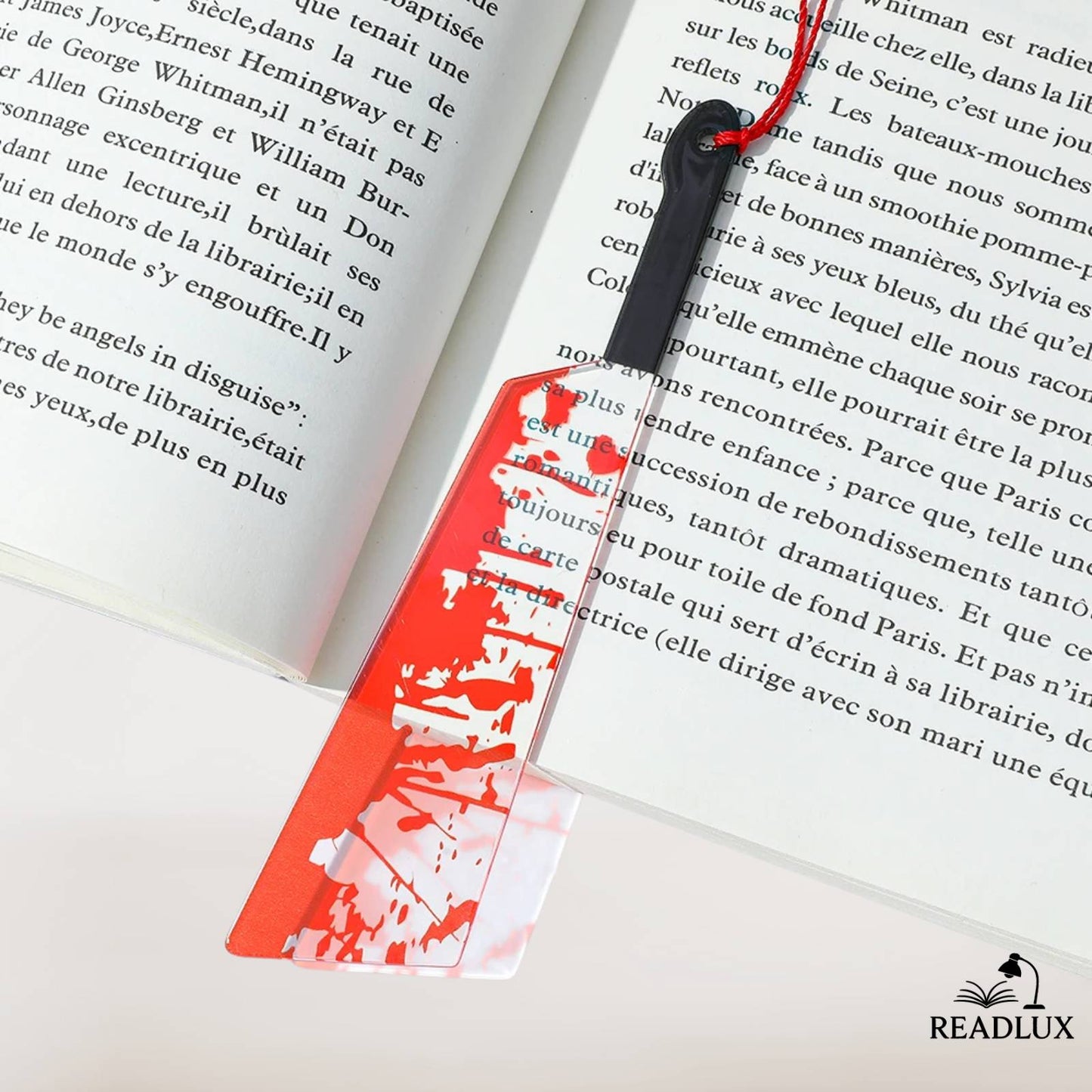 Marque-page original avec éclaboussures rouges et pompon décoratif sur un livre