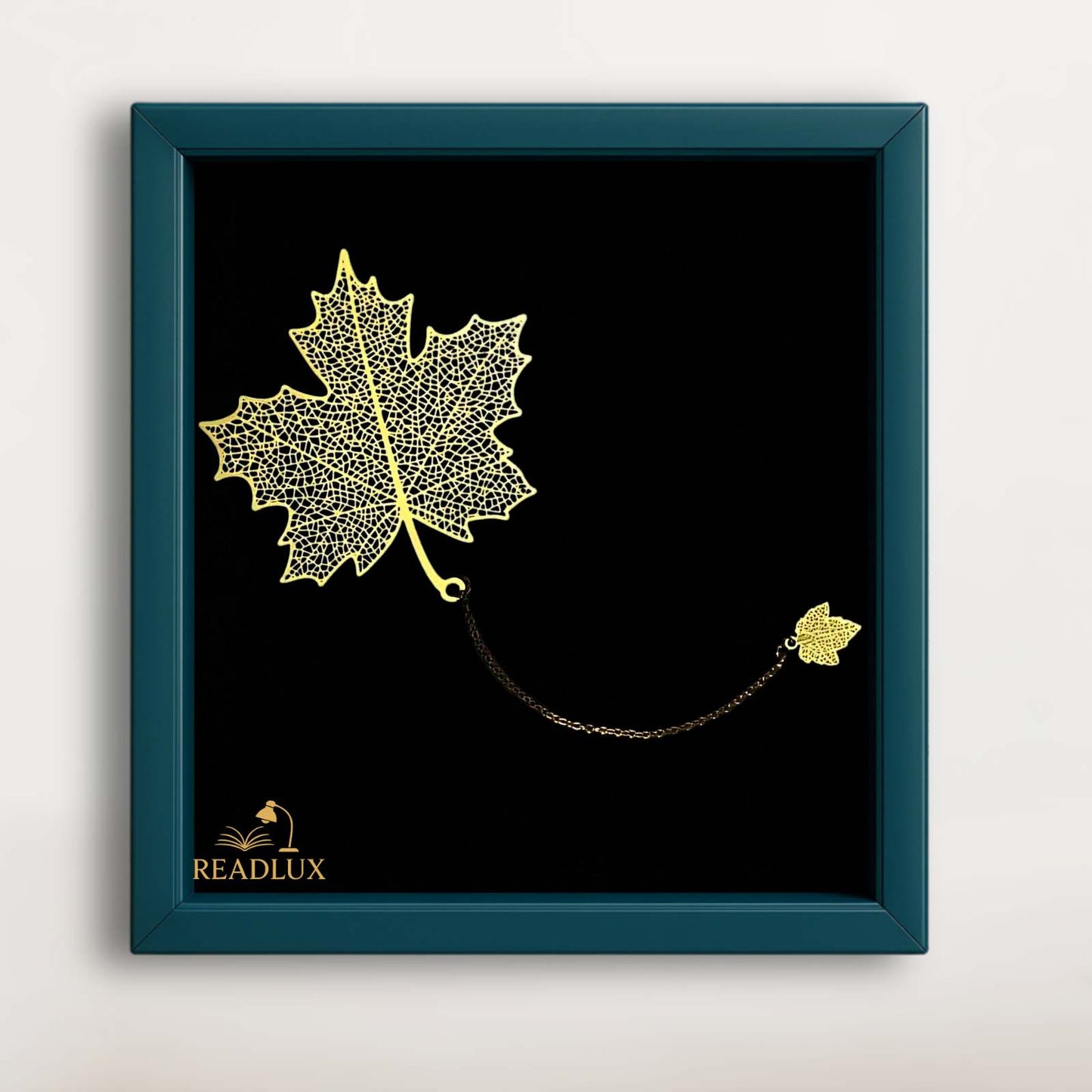 Marque-page en métal doré en forme de feuille d'érable, suspendu par une chaîne fine sur fond noir