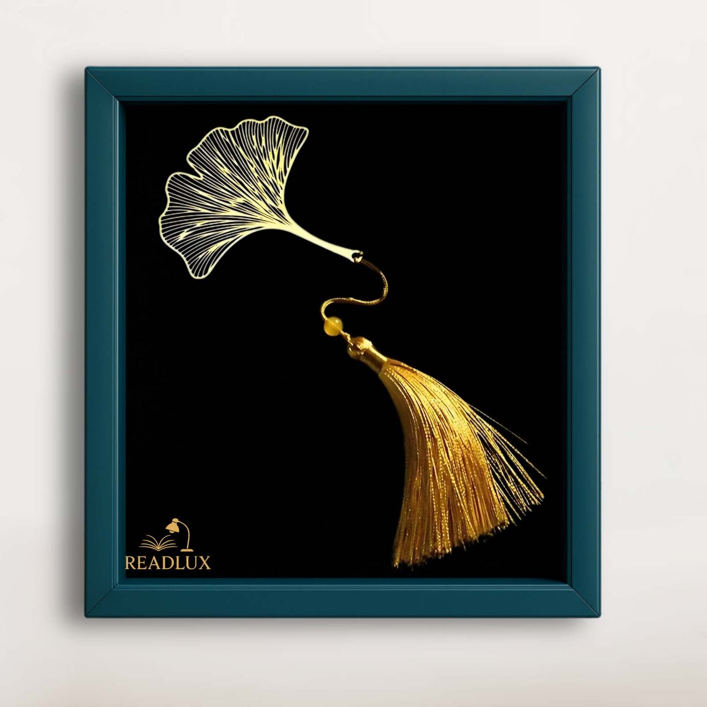 Marque-page en métal doré en forme de ginkgo biloba avec un pompon doré sur fond noir