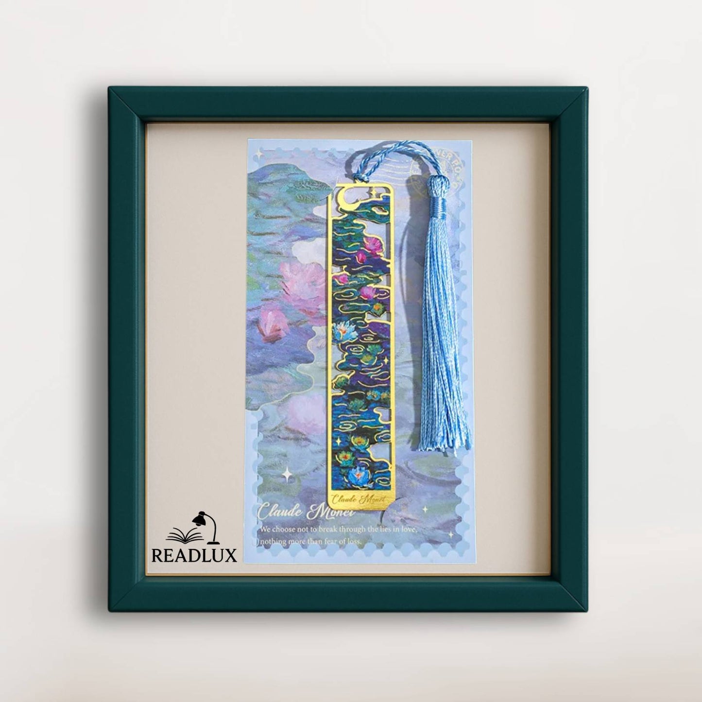 Marque-page en métal creux, motif floral coloré sur fond bleu avec un pompon en fil bleu