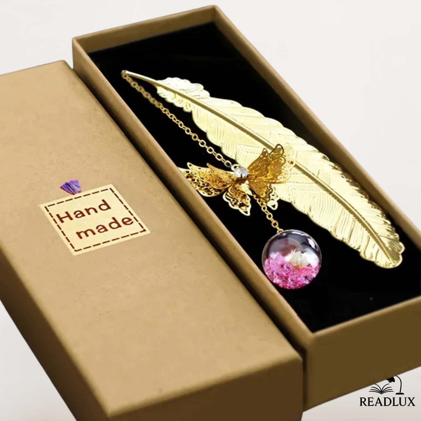 Marque page plume dorée avec pendentif rose et papillon, présenté dans une boîte cadeau élégante