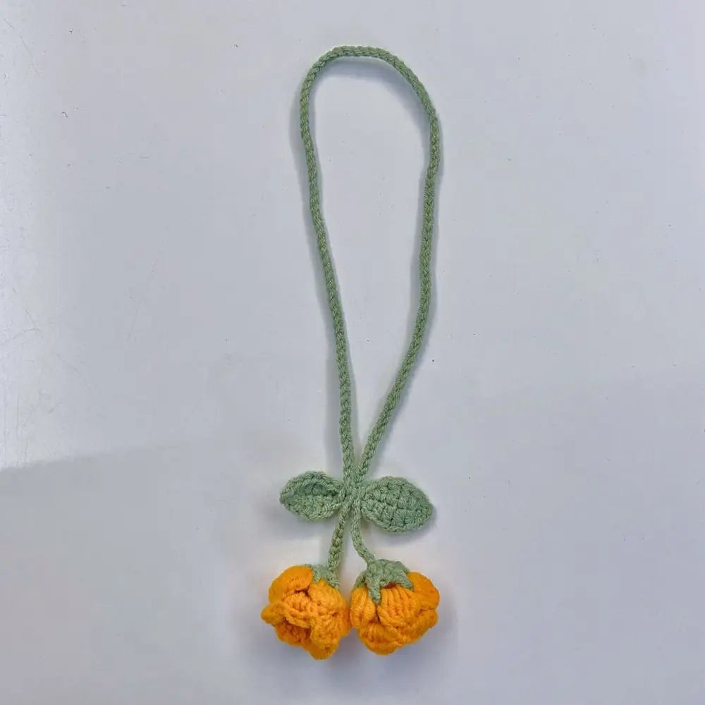 Marque-page en tricot avec deux fleurs jaunes et des feuilles vertes sur un fond blanc