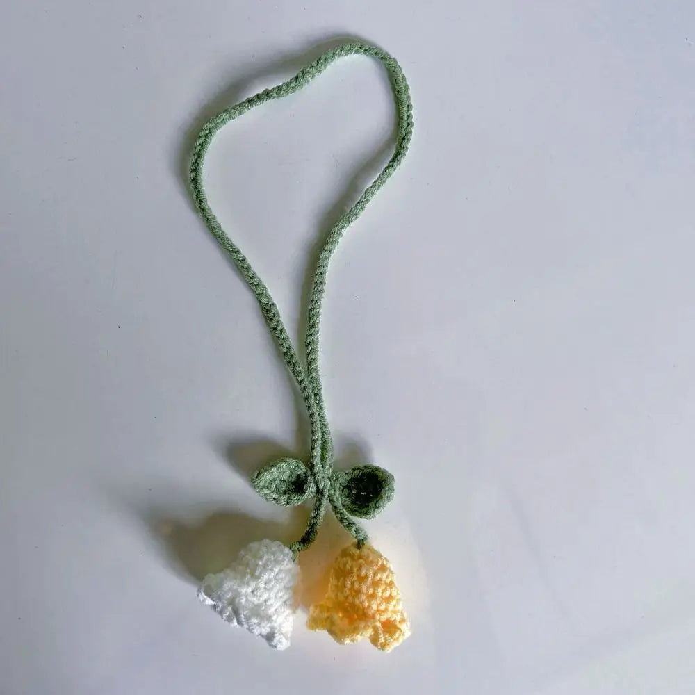 Marque-page en tricot avec deux fleurs, l'une blanche et l'autre jaune, sur fond blanc