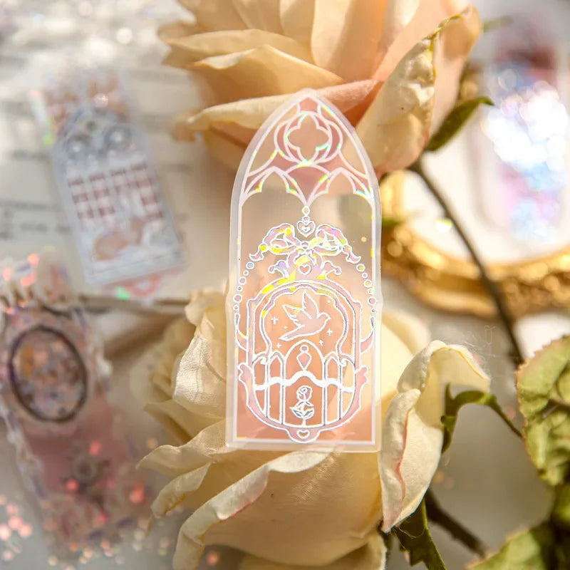 Marque-page en PVC translucide avec motifs colorés, posé sur des roses pâles et un décor élégant