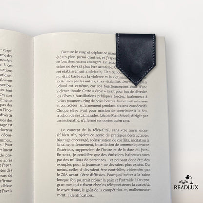 Marque-page en cuir noir magnétique posé sur une page d'un livre ouvert, décor sobre et élégant