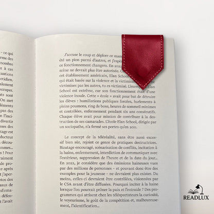 Marque-page en cuir rouge magnétique posé sur une page d'un livre ouvert, décor sobre et élégant