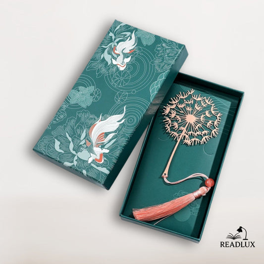 Marque page métal pissenlit rose cuivré avec pompon et perle, présenté dans une boîte cadeau illustrée élégante.
