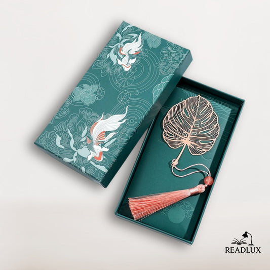 Marque page en métal rose doré en forme de feuille tropicale avec pompon, présenté dans un coffret vert Readlux