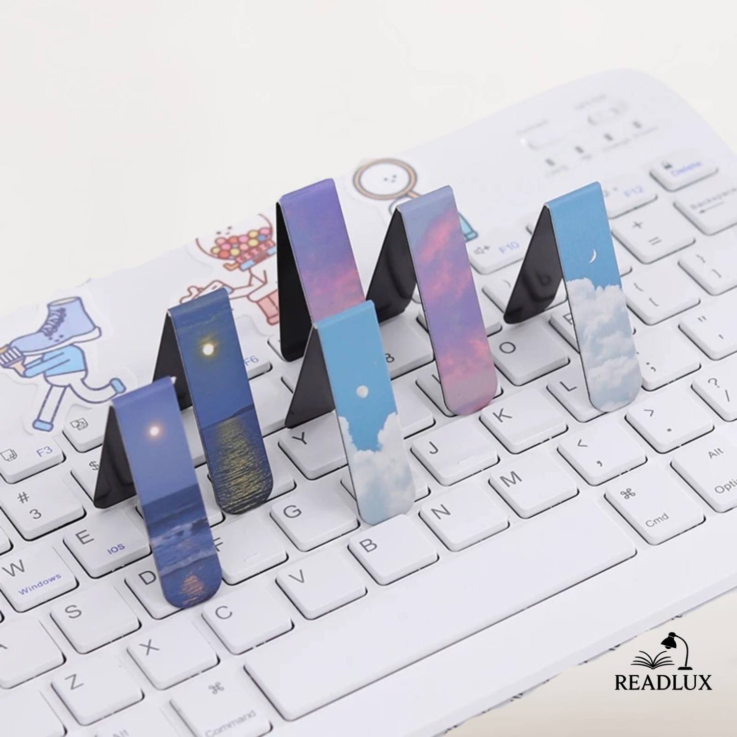 Des marque-pages magnétiques aux motifs de nuages et de ciel, posés sur un clavier blanc