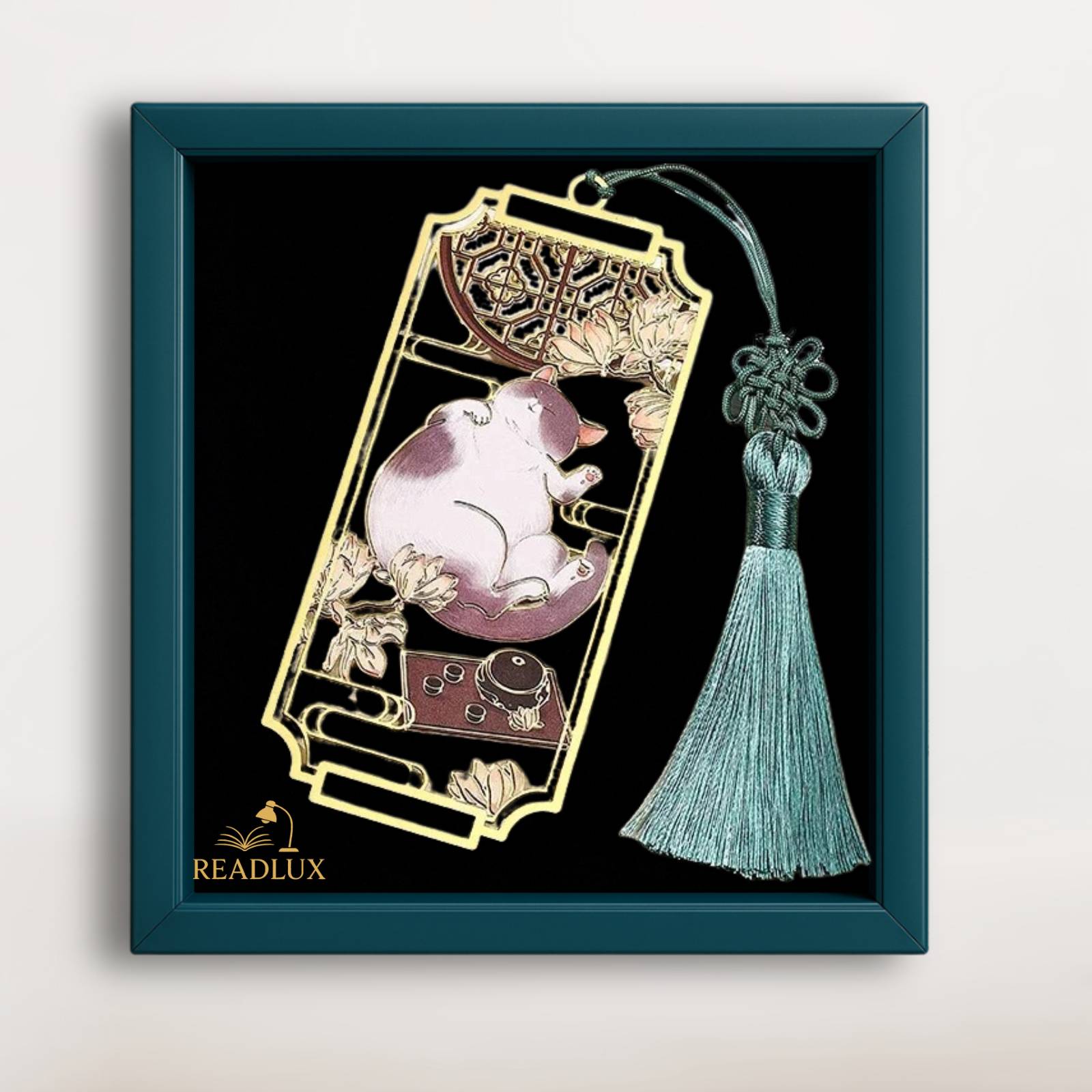 Marque page en métal doré avec chat blanc endormi, fleurs ajourées et pompon vert élégant.