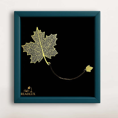Marque-page en métal doré en forme de feuille d'érable, suspendu par une chaîne fine sur fond noir