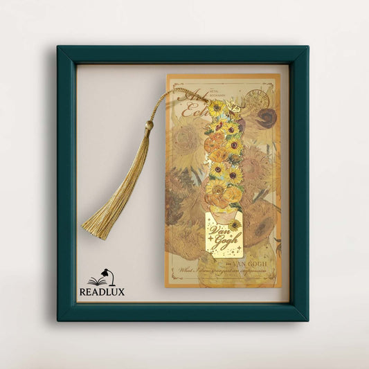 Marque-page en métal doré avec un long gland, affichant des tournesols sur fond beige et un cadre vert