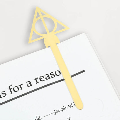 Un marque-page en métal doré avec un motif triangulaire et circulaire, posé sur une page blanche de livre