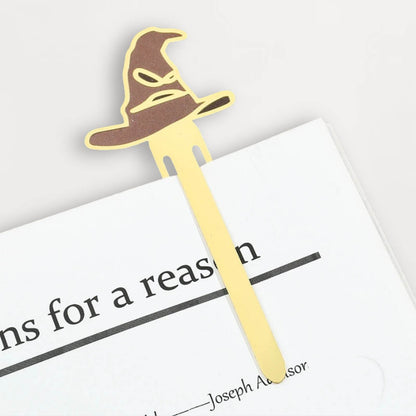 Marque-page en métal doré représentant un chapeau de sorcier posé sur une page d'un livre ouvert