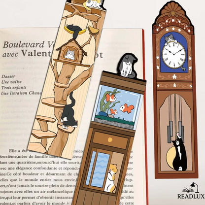 Marque pages papiers chats insérés dans un livre, avec illustrations d’arbre à chat, aquarium et horloge ancienne.