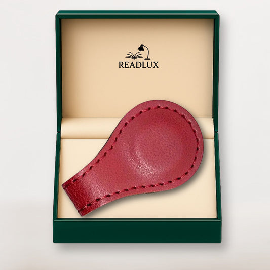 Marque-page en cuir rouge, légèrement texturé, posé dans une boîte verte avec intérieur beige, élégant et raffiné