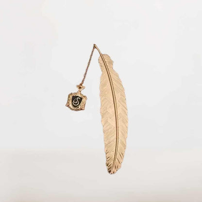 Marque page plume dorée en métal avec insigne noir suspendu, style sorcier élégant, mystérieux et symbolique