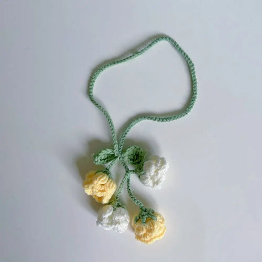 Marque-page tricoté avec des fleurs jaunes et blanches, tige verte, sur fond blanc