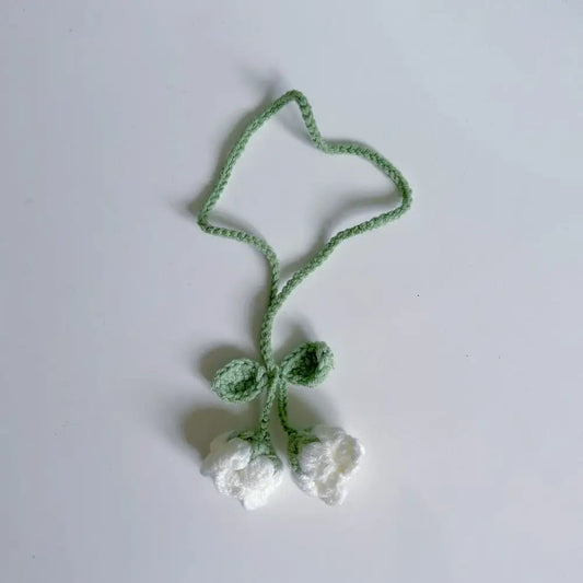 Marque-page en tricot avec deux fleurs blanches et une tige verte sur fond blanc