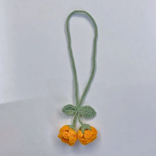 Marque-page en tricot avec deux fleurs jaunes et des feuilles vertes sur un fond blanc