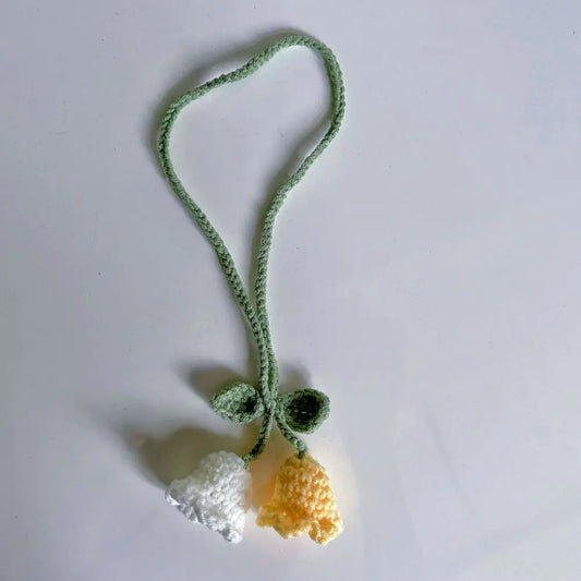 Marque-page en tricot avec deux fleurs, l'une blanche et l'autre jaune, sur fond blanc