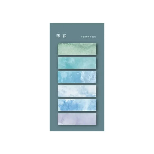 Des marqueurs autocollants transparents aux nuances de bleu et vert, avec des motifs aquarelle sur fond gris