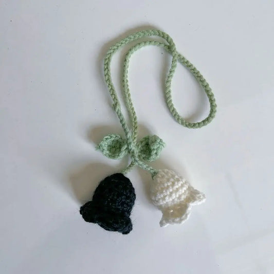 Marque-page en tricot avec une cloche noire et une cloche blanche, relié par une corde verte