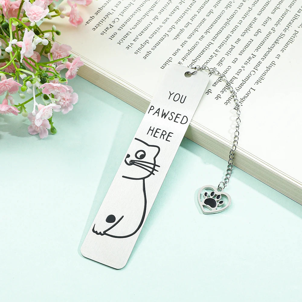 Marque-page en métal argenté avec un dessin de chat et un pendentif en forme de patte, sur fond pastel