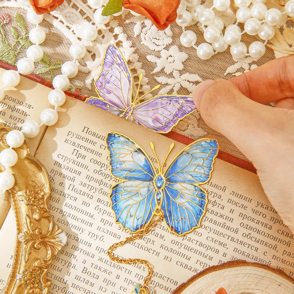 Deux marque-pages en métal en forme de papillon, l'un bleu et l'autre violet, sur une page de livre