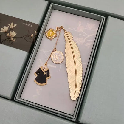 Marque-page en métal doré en forme de plume, avec un pendentif représentant une robe de sorcier et un écusson