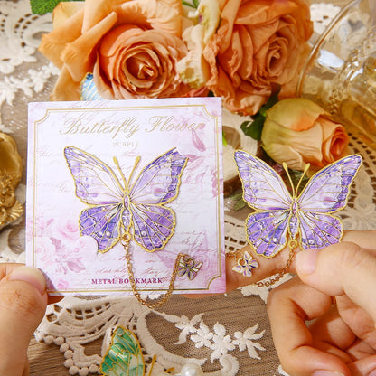 Un marque-page en métal en forme de papillon violet, posé sur un fond floral avec des roses et de la