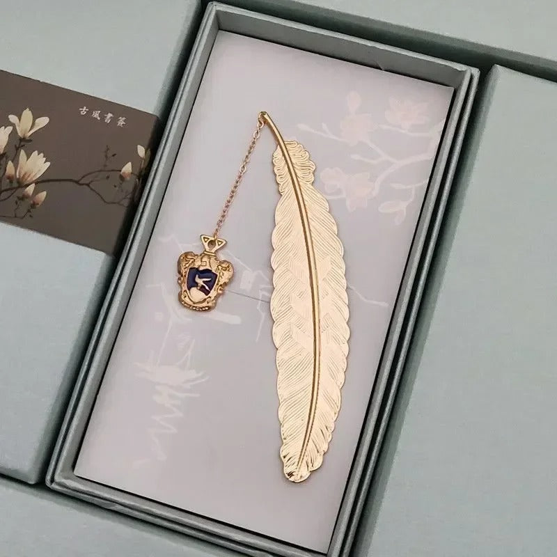 Marque page plume dorée en métal avec blason bleu nuit suspendu, finition ciselée, style sorcier noble et discret